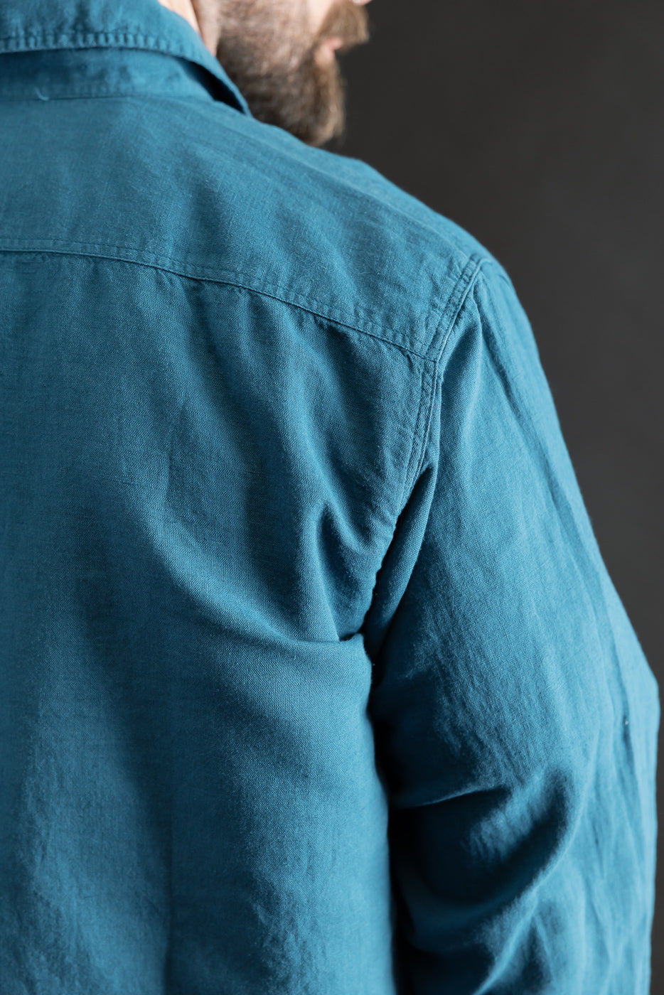 Close-up of men's Indigofera McAllen ocean blue canvas shirt, back shoulder detail, male model 5'9