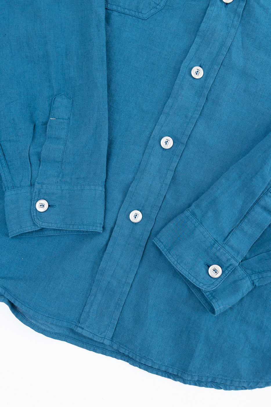 Close-up of Indigofera McAllen ocean blue canvas shirt front, showing cuff, white buttons and fabric texture