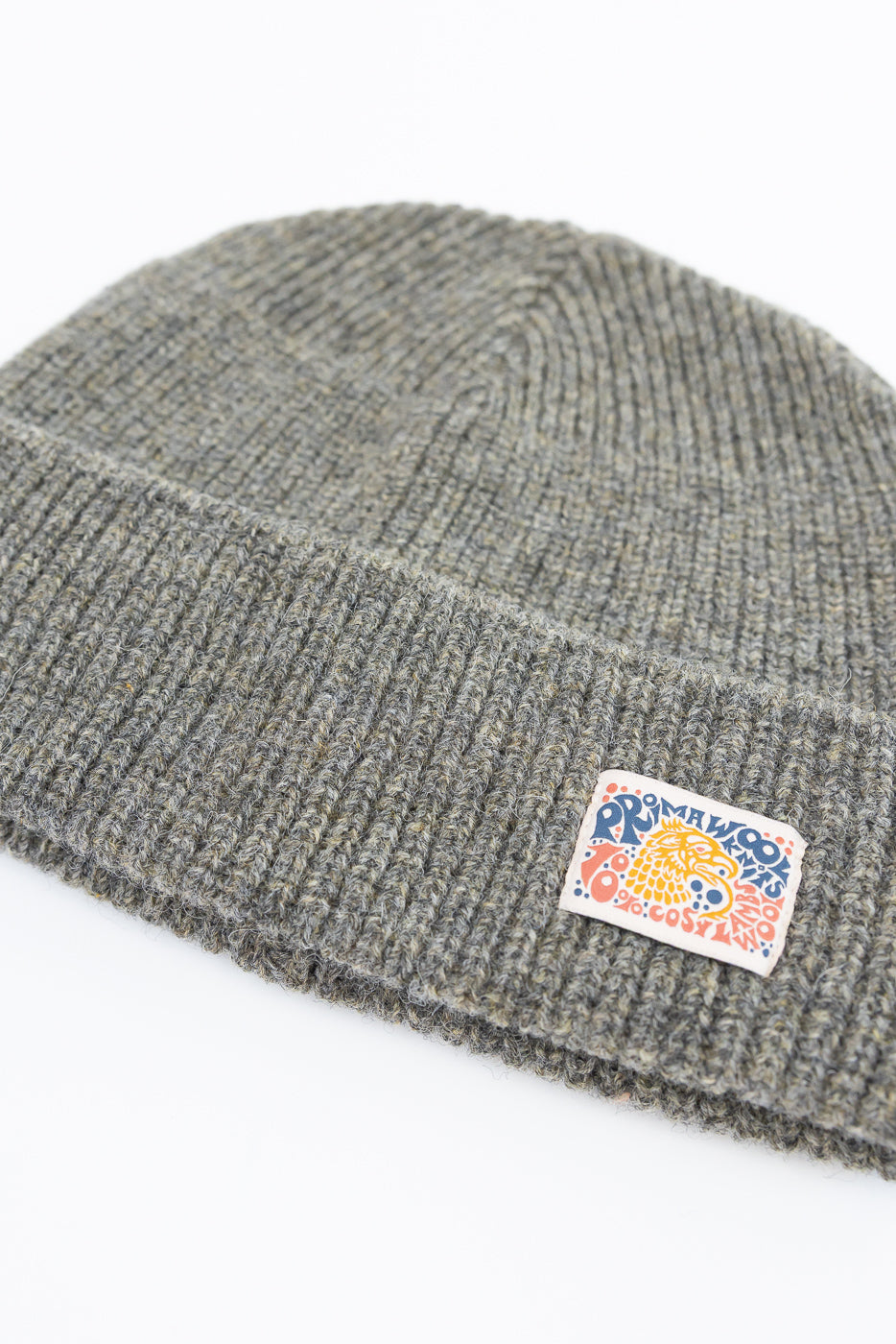 Close-up of the front of a grey ribbed knit beanie featuring a colorful embroidered patch.