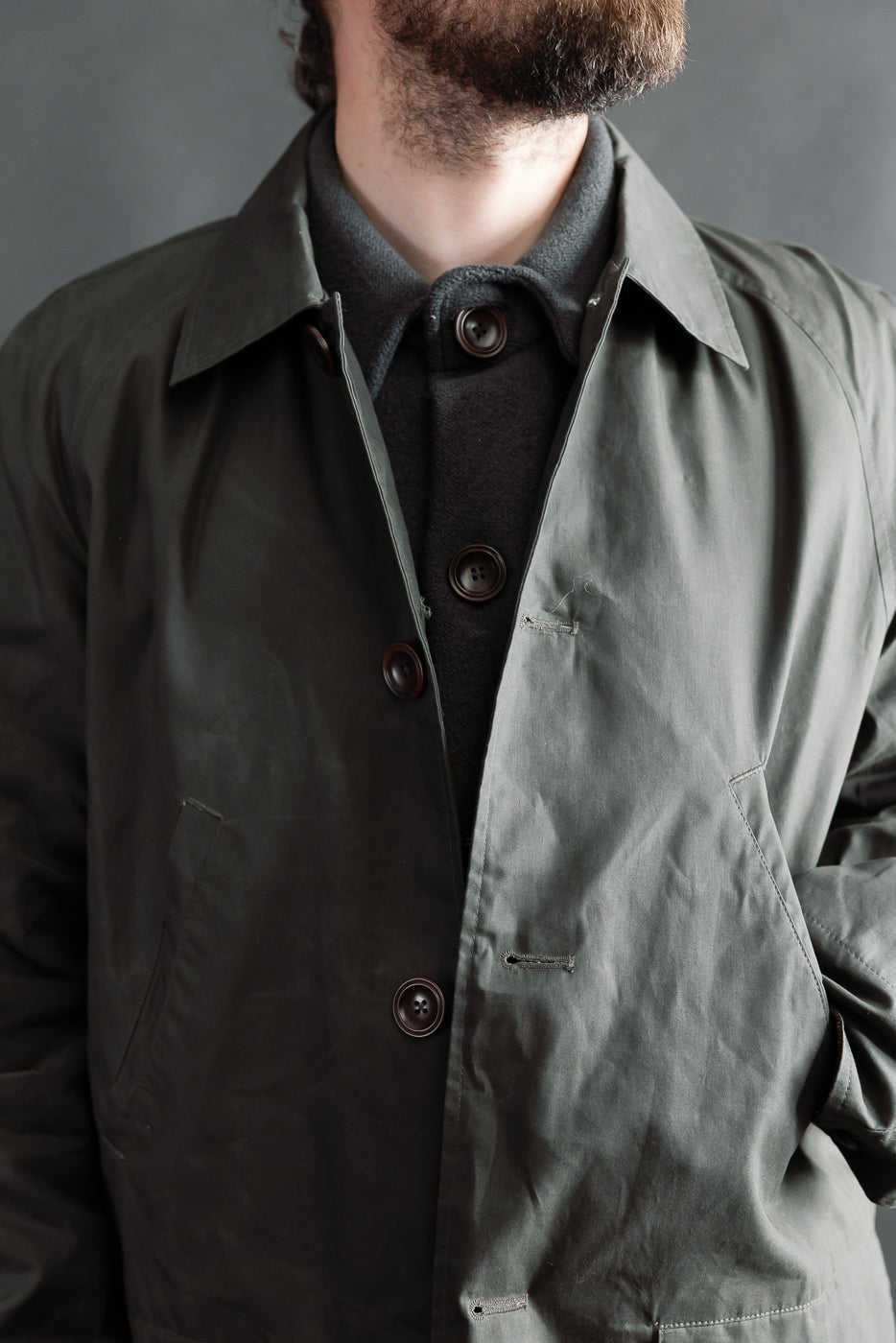 Close-up front view of Indigofera Raven coat in coated cotton twill, dark grey, on male model 5'9