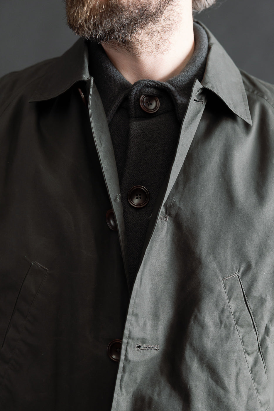 Close-up front view of Indigofera Raven Coat in dark grey coated cotton twill on 5'9