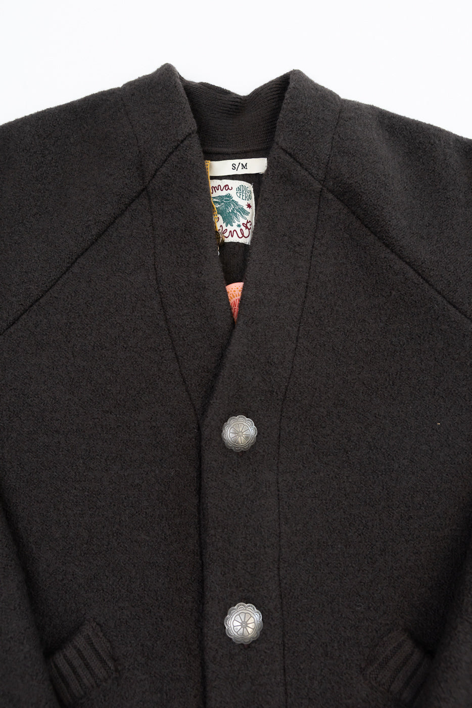Close-up front view of a dark grey wool jacket showing the collar, tag, and decorative buttons.