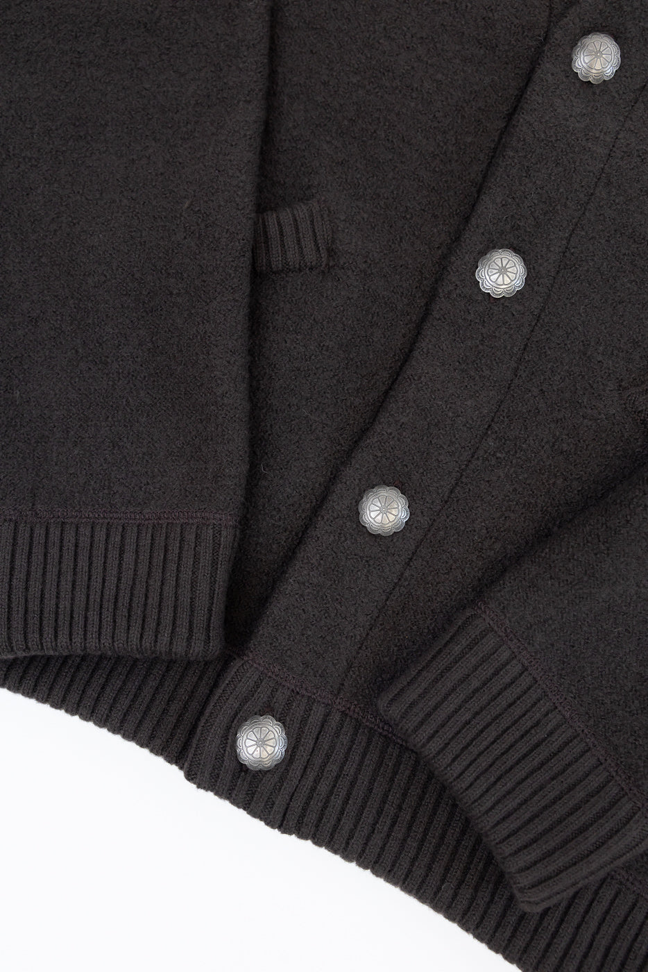 Close-up front view of dark brown cardigan showing textured fabric and silver snap buttons.