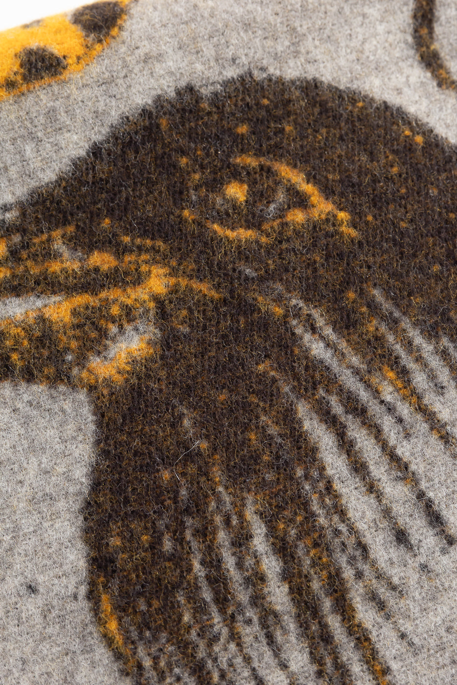 Close-up of Indigofera Skata blanket fabric texture in grey, brown, and yellow, showing design details.