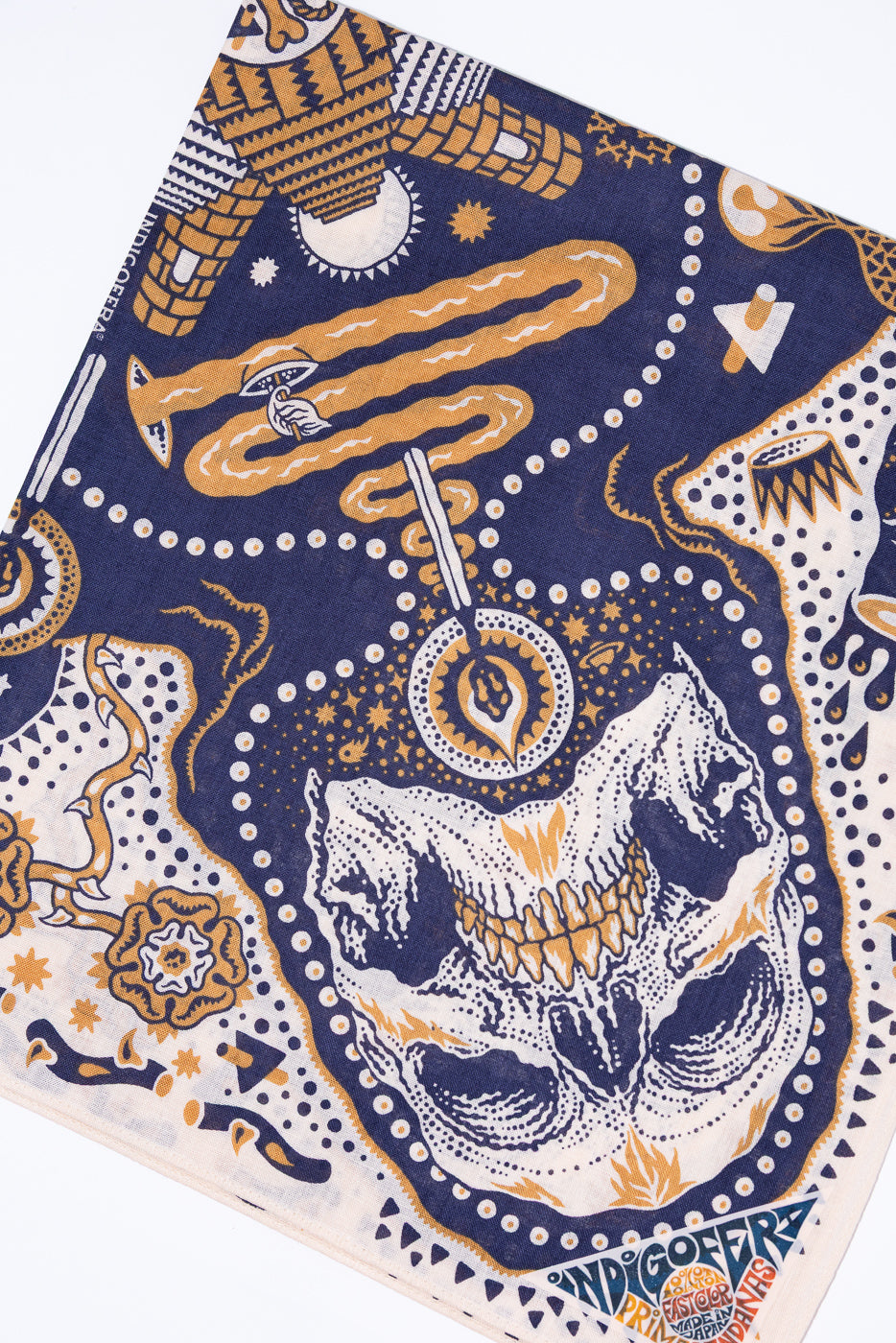 Front view of patterned bandana with skull, moon, and geometric designs in navy, gold, and white.