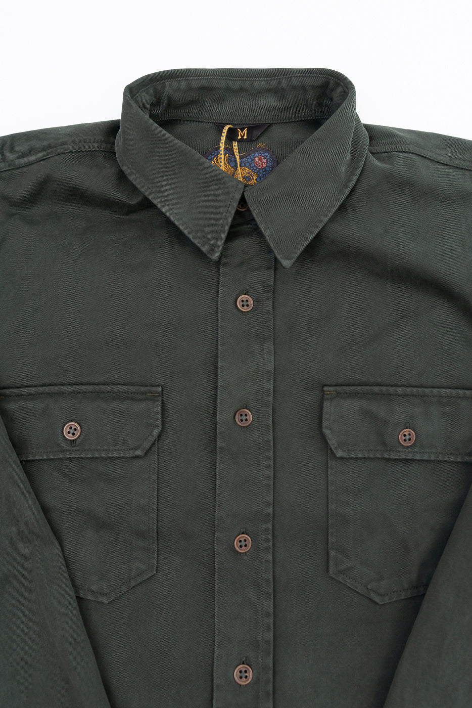 Close-up of the front of a dark green shirt showing the collar, buttons, and chest pockets.