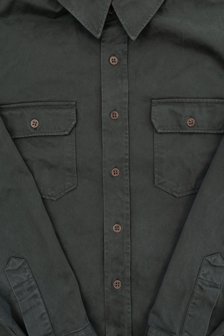 Close-up front view of a dark olive green button-down shirt showing chest pockets and buttons.