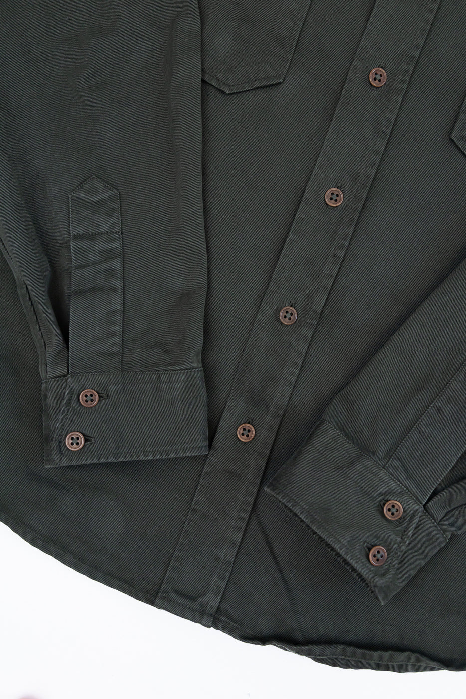 Close-up front view of a dark olive button-down shirt showing fabric texture and button details.