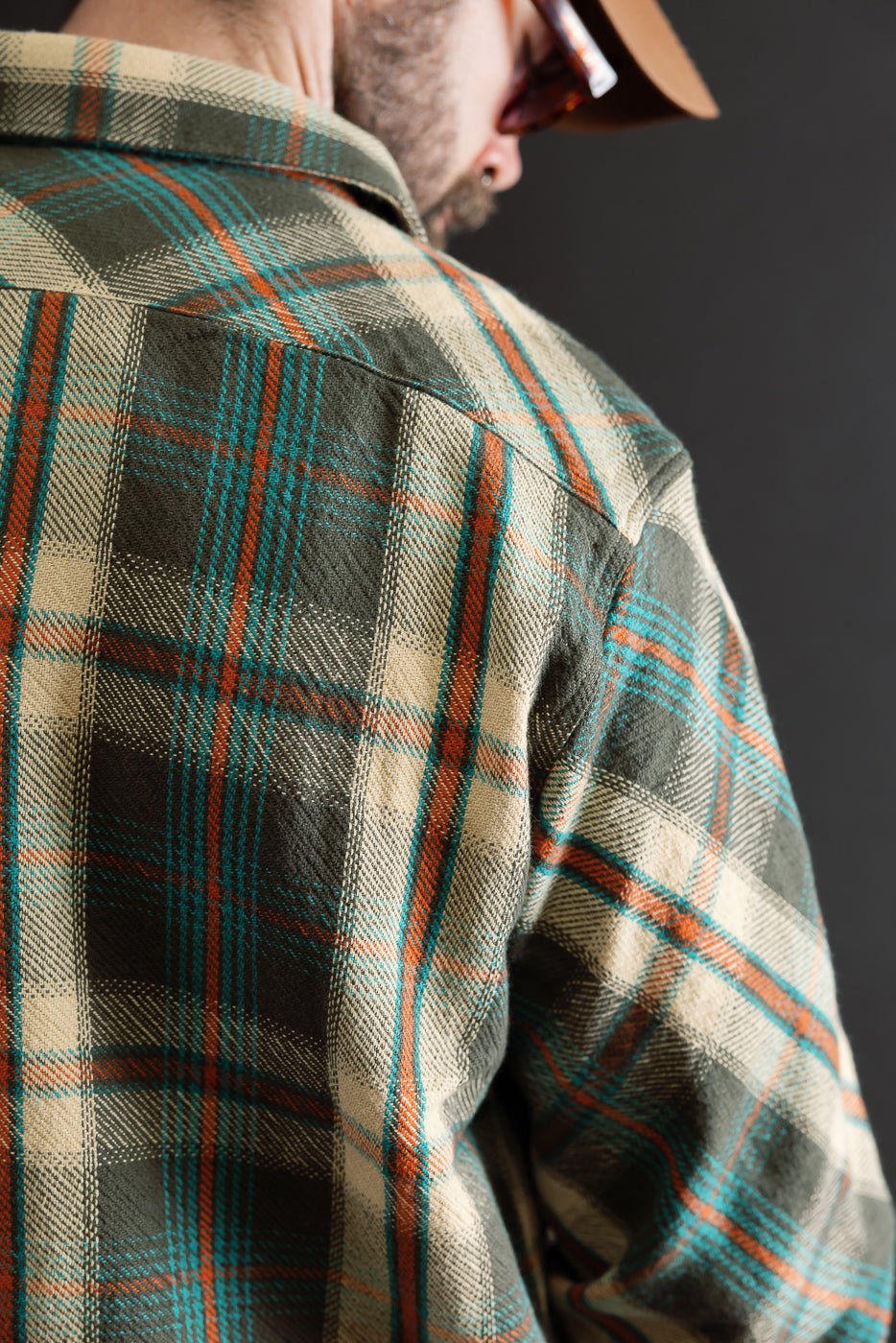 Close-up back view of a plaid flannel shirt showing fabric texture and shoulder seam.