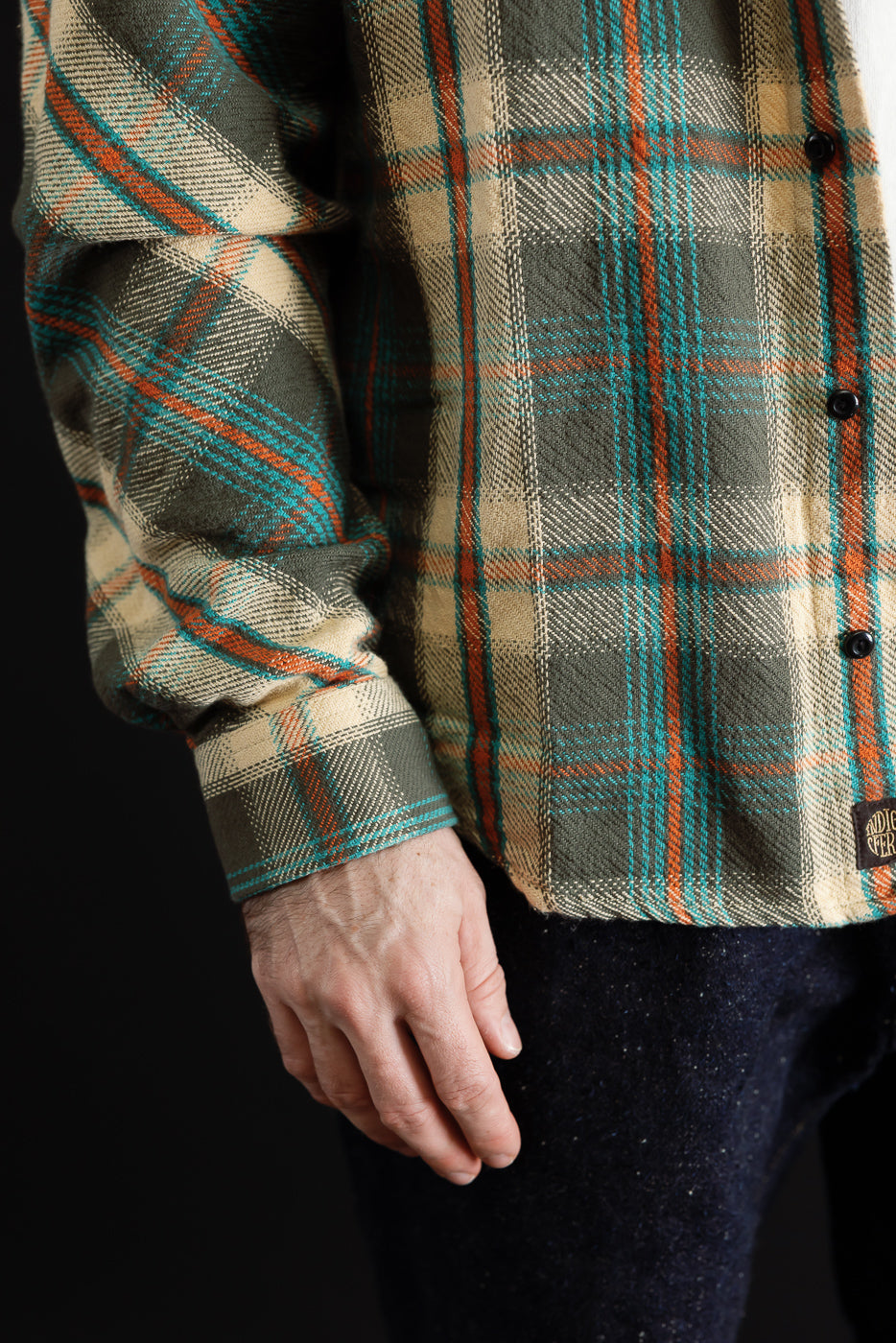Close-up side view of a plaid flannel shirt sleeve and torso showing fabric texture.