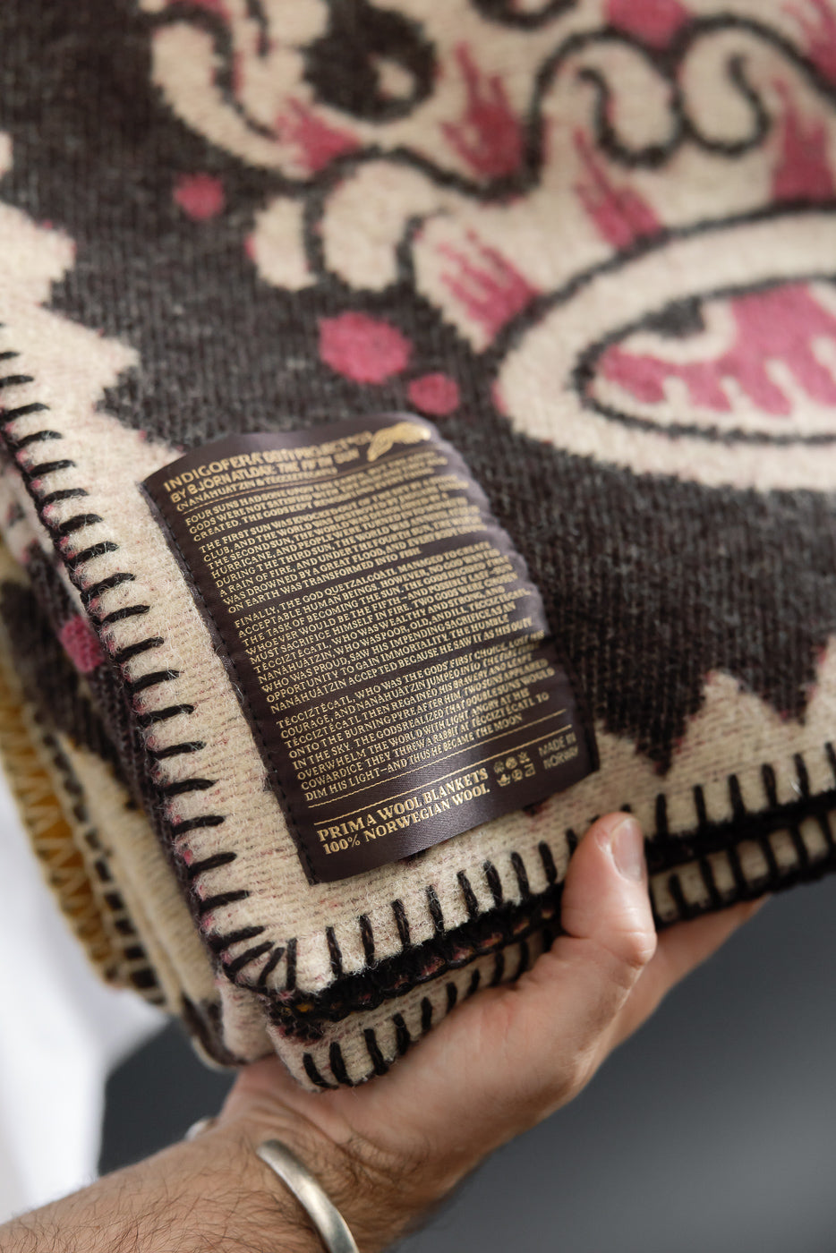 Close-up of a 100% Norwegian wool blanket's fabric texture and detailed informational tag.