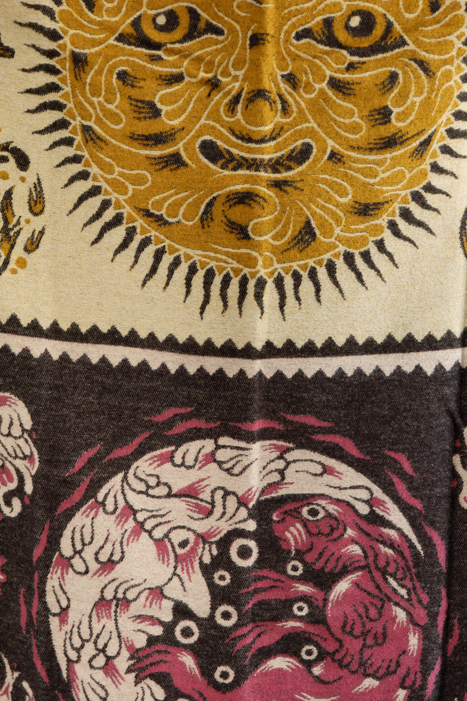 Close-up of fabric texture featuring intricate sun and animal patterns.