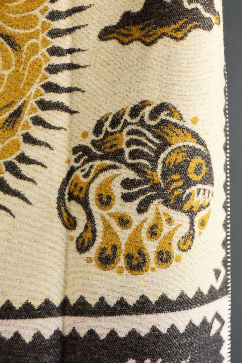 Close-up detail of the side hem showing a gold fish and sun graphic on cream fabric.