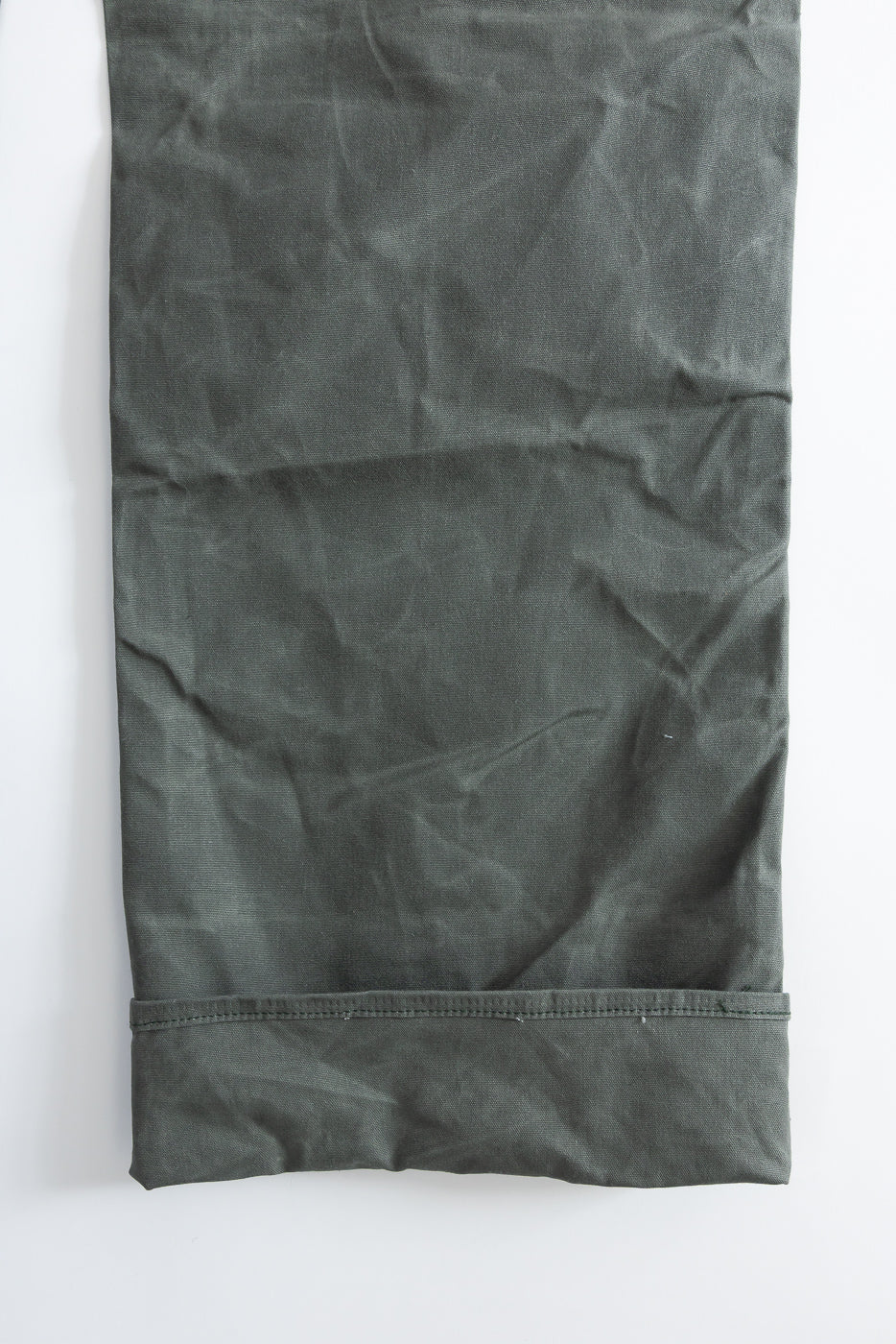 Close-up of front lower leg hem, greyish coated canvas double knee pants, fabric texture visible