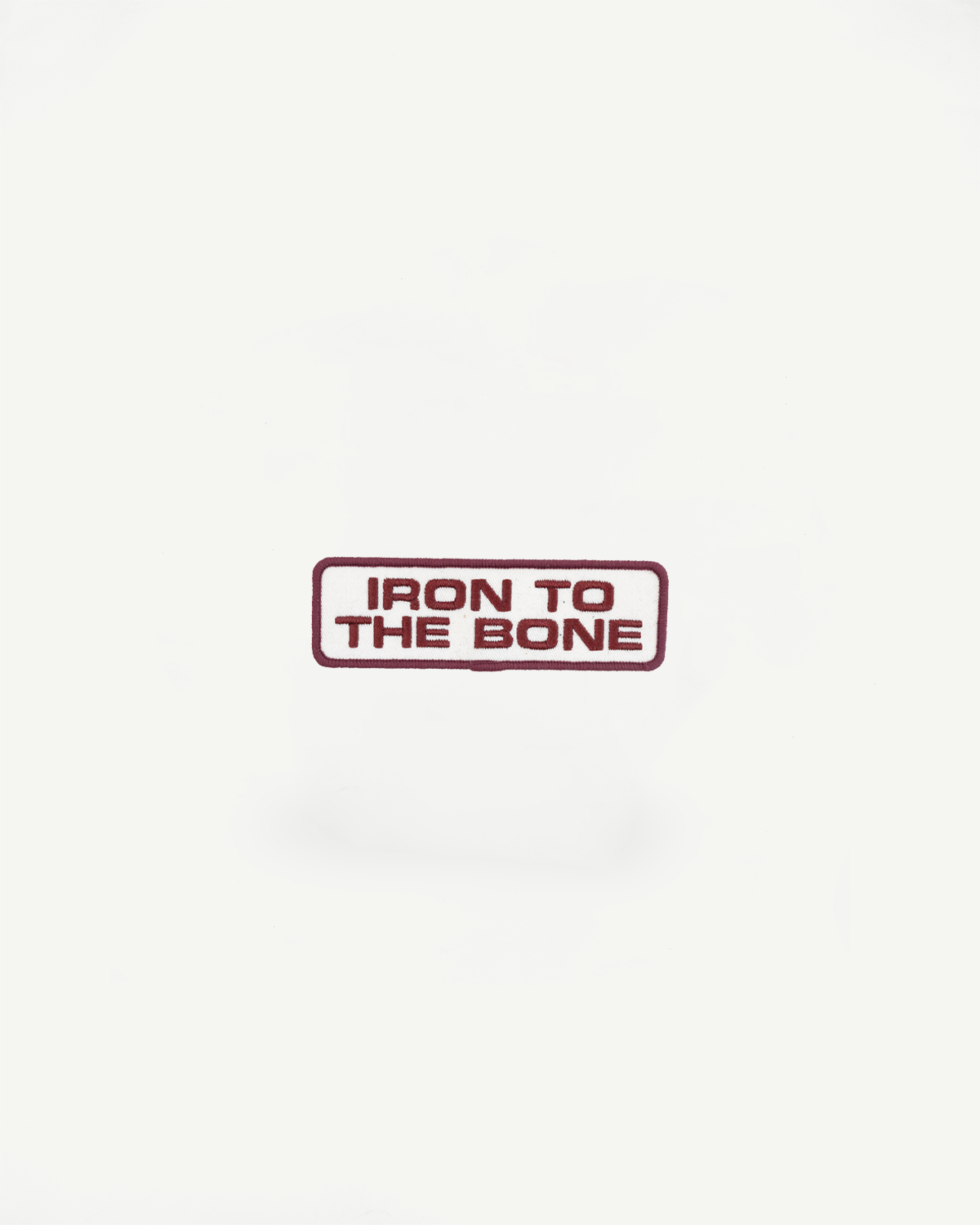 Iron to the Bone embroidered patch, front view, maroon text on white background with maroon border