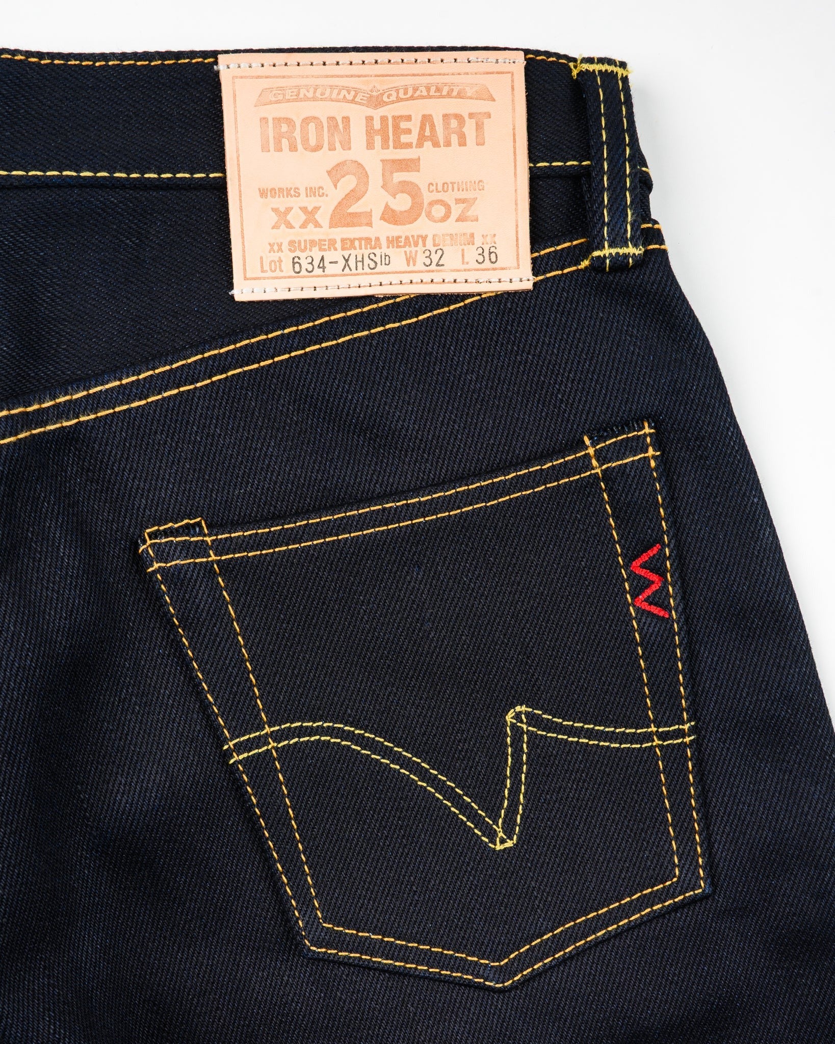 Close-up of Iron Heart 25oz selvedge denim jeans back pocket and leather patch, indigo-black, rear view, contrast stitching, at Dant contemporary casual apparel.