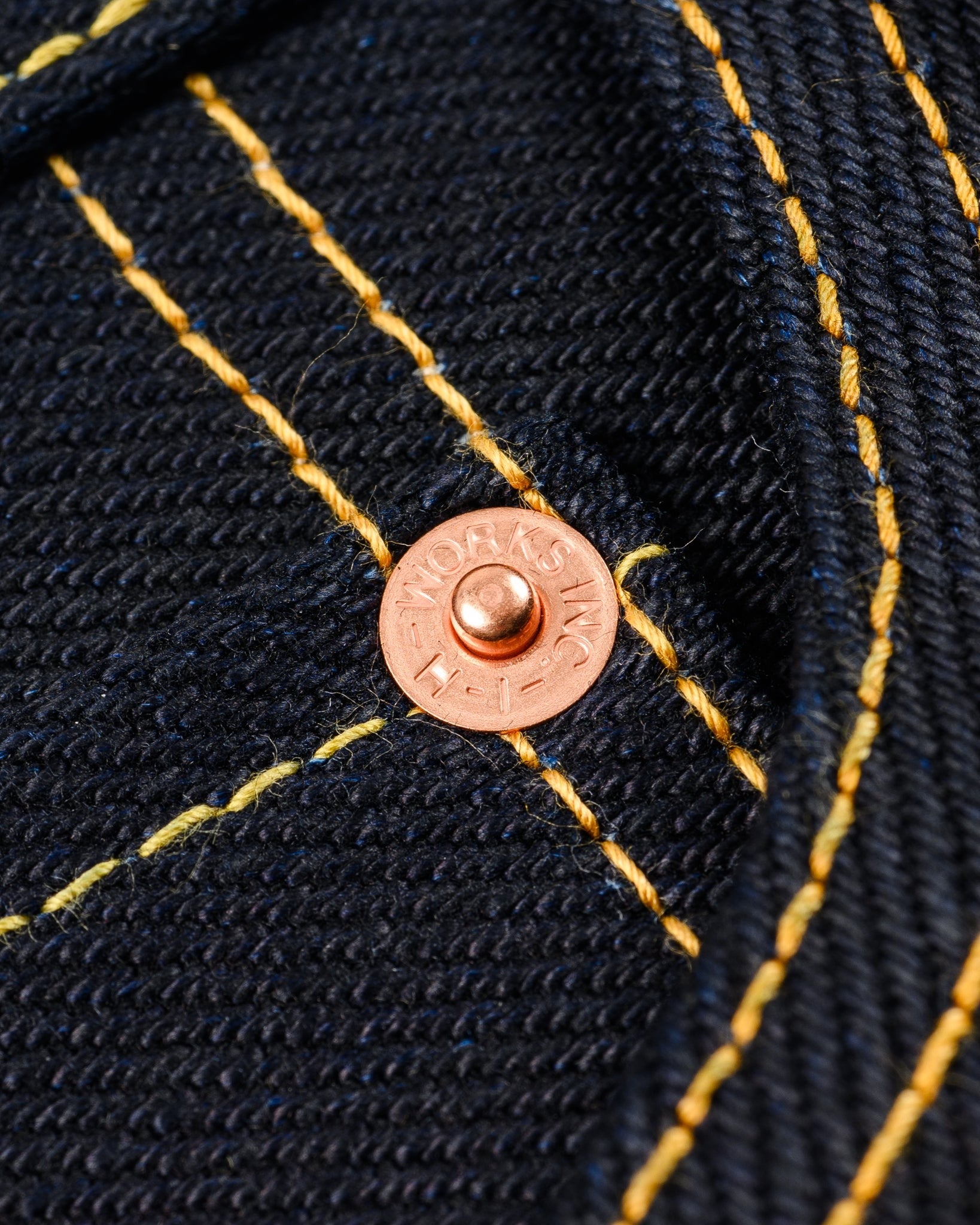 Close-up of Iron Heart 25oz selvedge denim, copper rivet, yellow stitching, pocket corner.