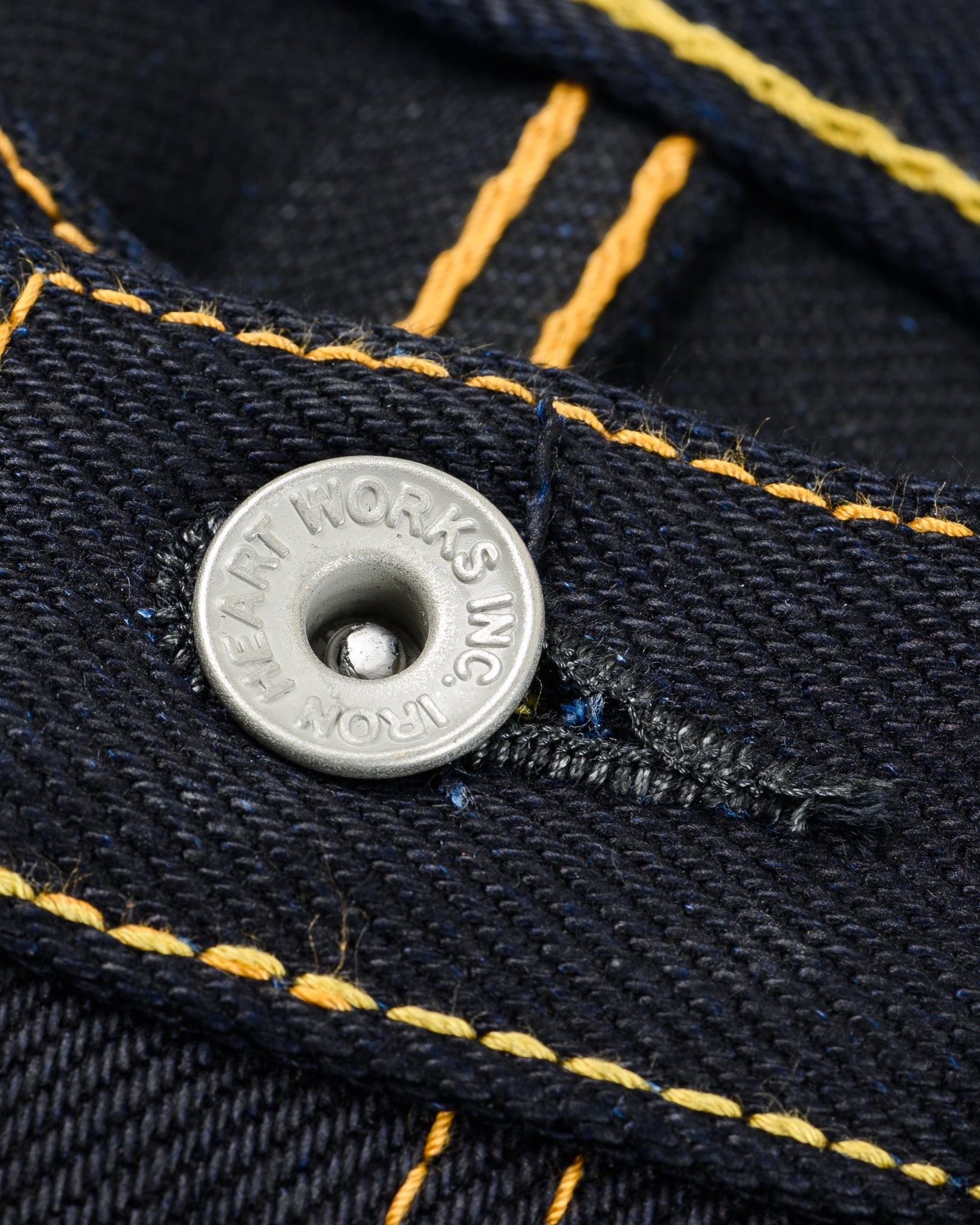 Close-up of Iron Heart IH-634-XHSib 25oz selvedge denim jeans button and yellow stitching, front waistband detail.
