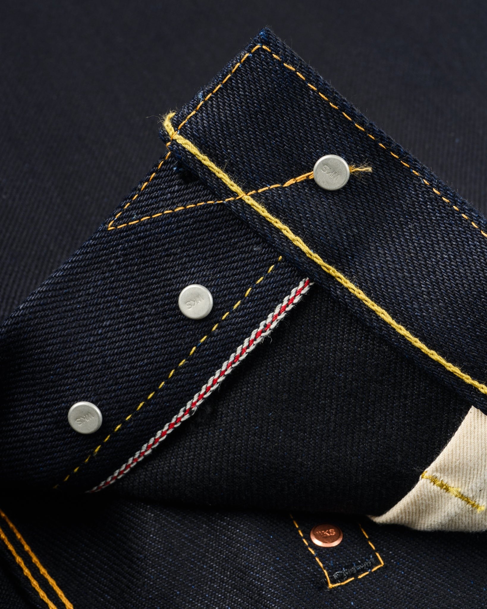 Close-up of Iron Heart IH-634-XHSib 25oz selvedge denim, front interior hem, showing rivets, yellow stitching, and red selvedge ID, contemporary casual jeans from Dant.