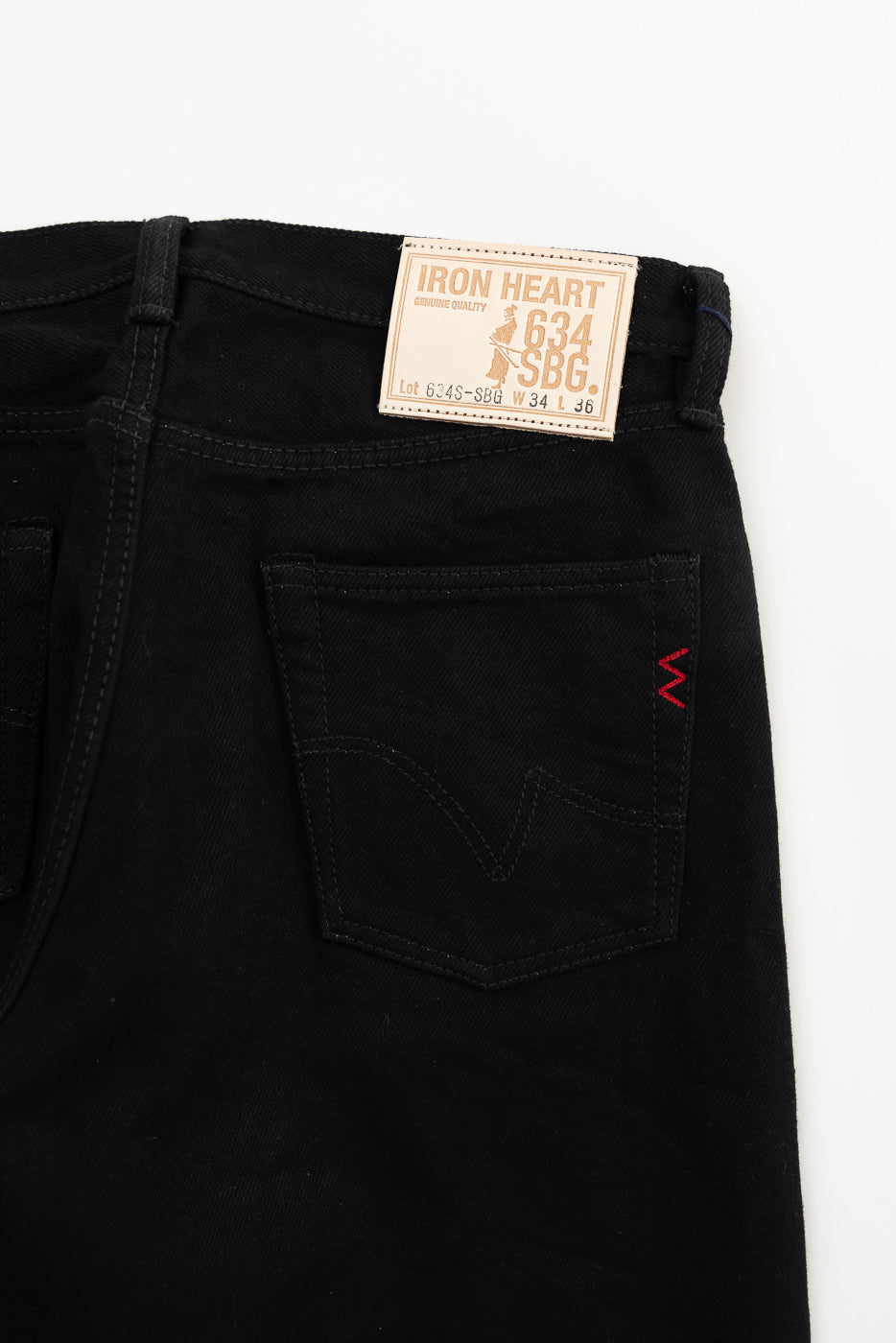 Close-up of Iron Heart IH-634S-SBG superblack selvedge denim, back pocket and leather patch, flat lay, rear view.