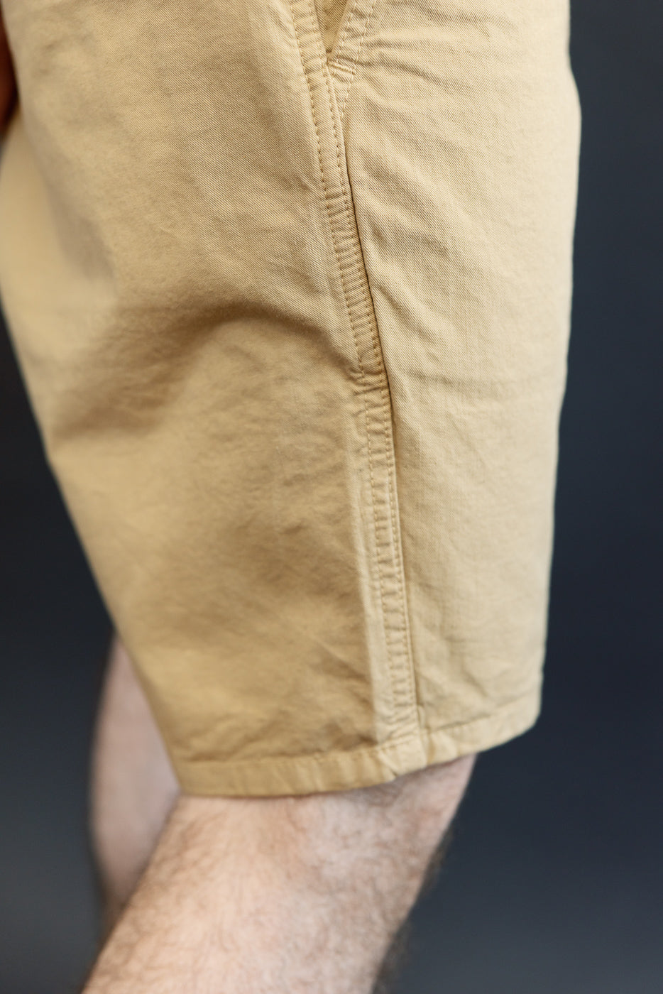 Close-up of male model's side, showing tan shorts hem and fabric texture