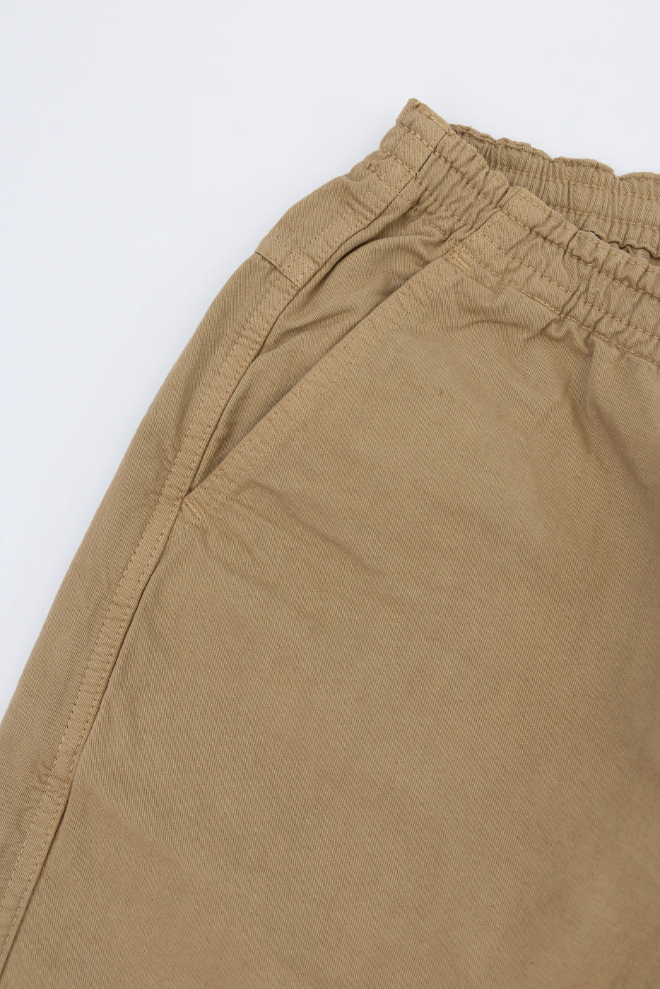 Close-up of tan casual pants waistband, elastic detail, and fabric texture