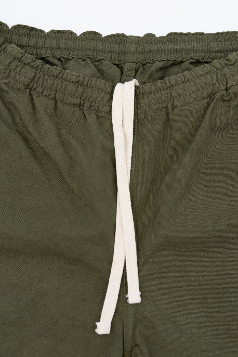 Close-up front view of olive green shorts with white drawstring and elastic waistband