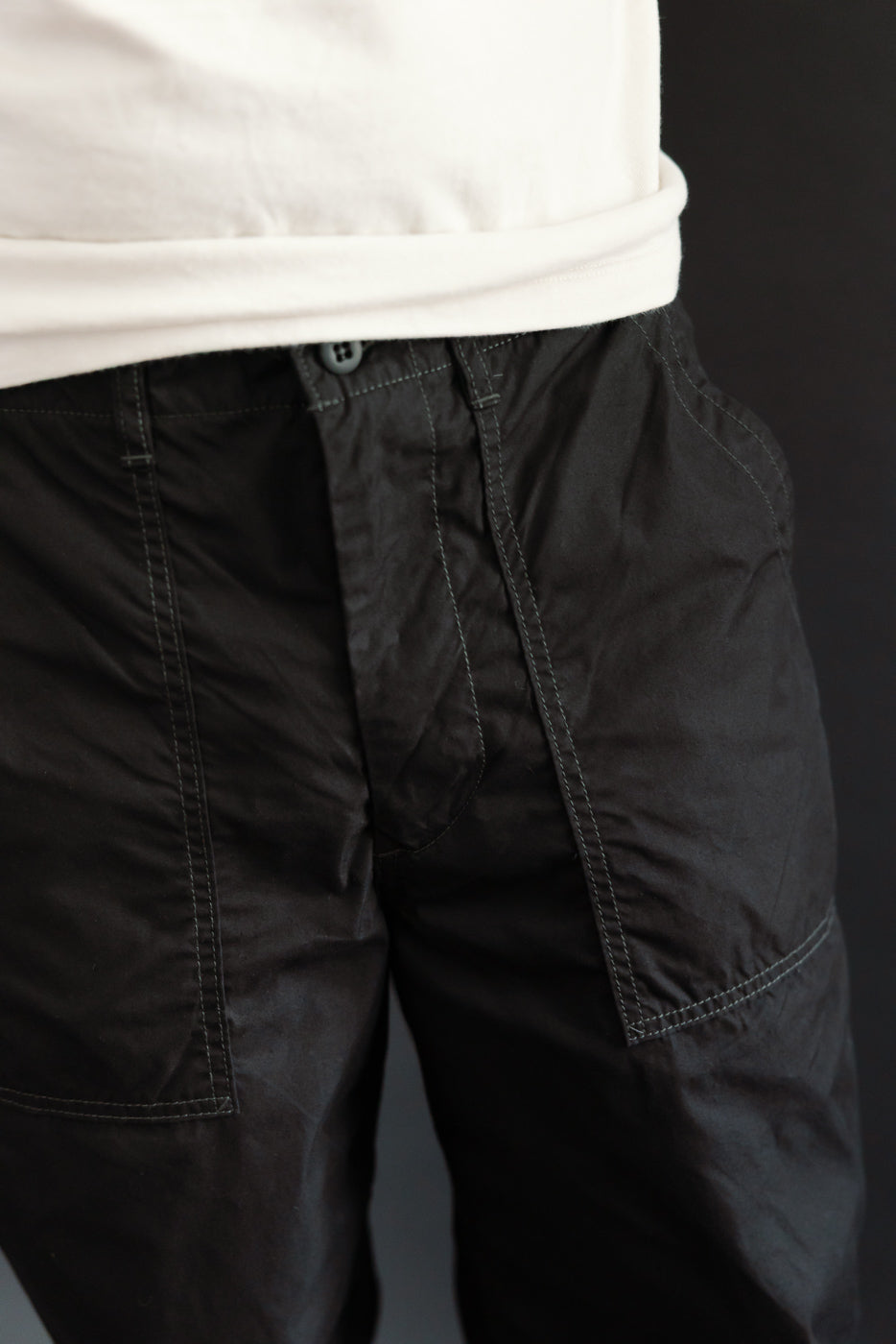 Close-up front view of black cargo shorts with button fly, worn by male model, 5'9