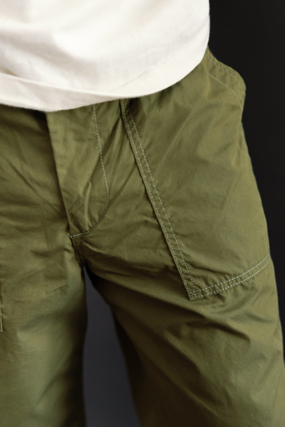 Close-up of olive green cargo pants front, showing pocket stitching, worn by male model 5'9