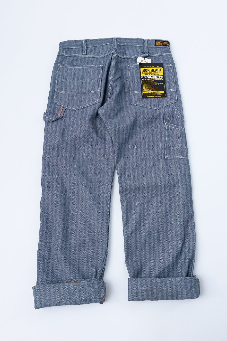 Back view of selvedge denim pants with rolled cuffs, showing back pockets and Iron Heart tag.