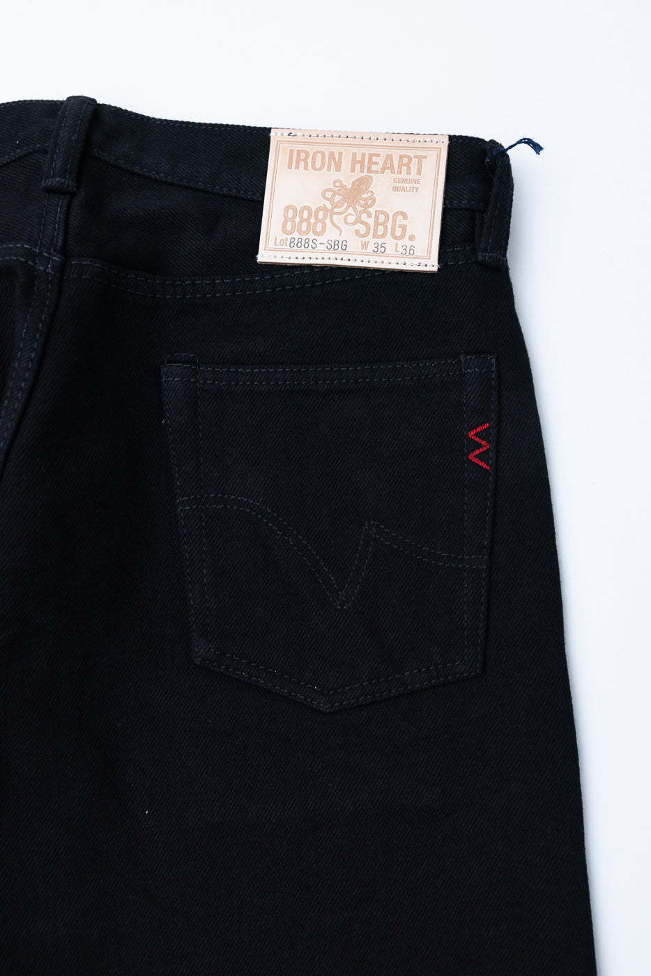 Close-up of black selvedge jeans back pocket with red stitching and Iron Heart tag, size W35 L36