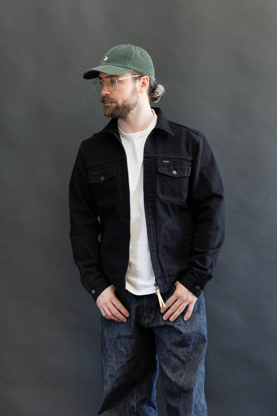 IHJ-123-OD - 14oz Broken Twill Selvedge Denim Work Jacket - Indigo Overdyed Black, worn by a casually dressed man, showcasing its relaxed fit and intricate details like snap pockets and adjustable cuffs.