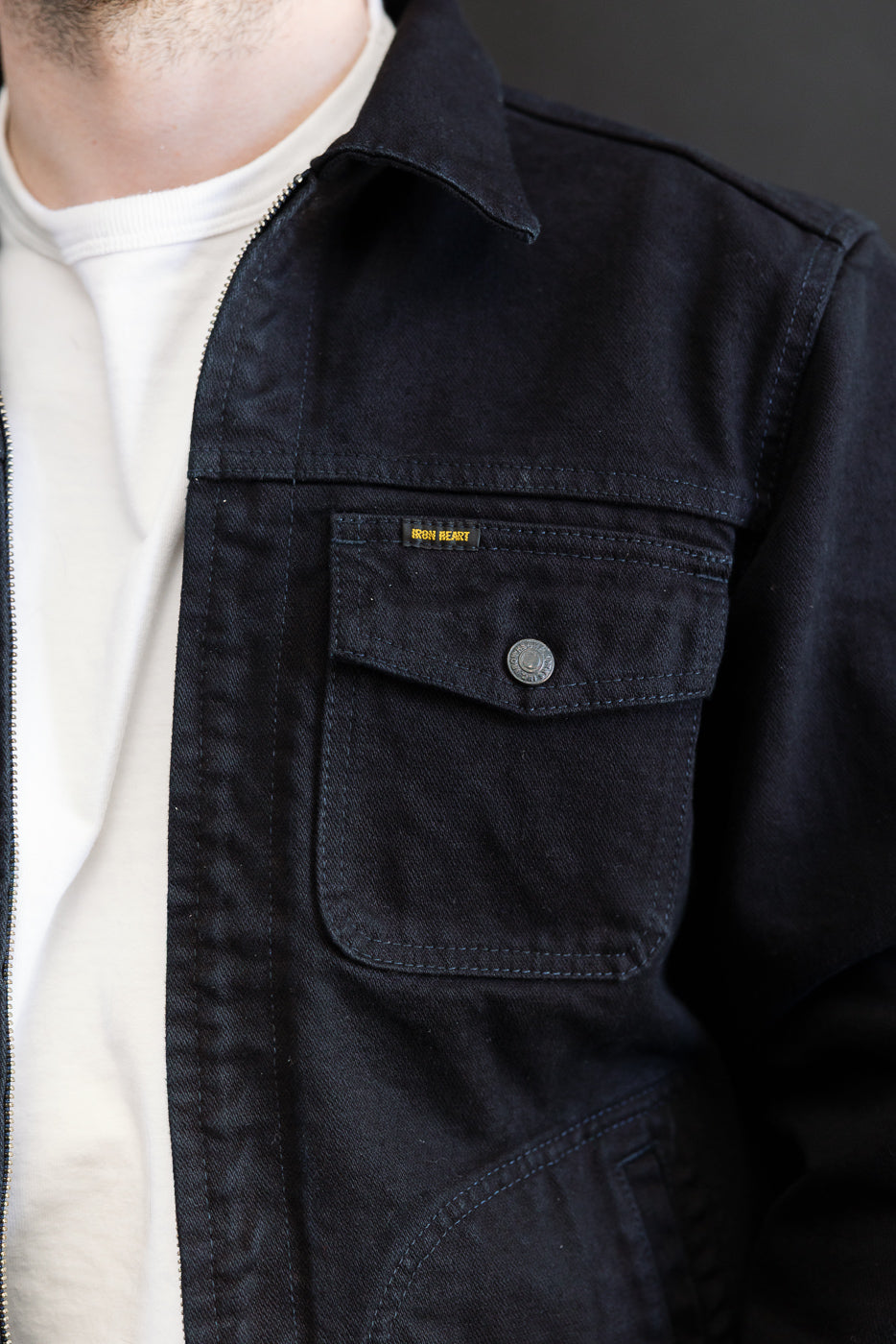 IHJ-123-OD - 14oz Broken Twill Selvedge Denim Work Jacket features a near-black denim with a visible left chest pocket, metal snap button, and Iron Heart label, layered over a white T-shirt.