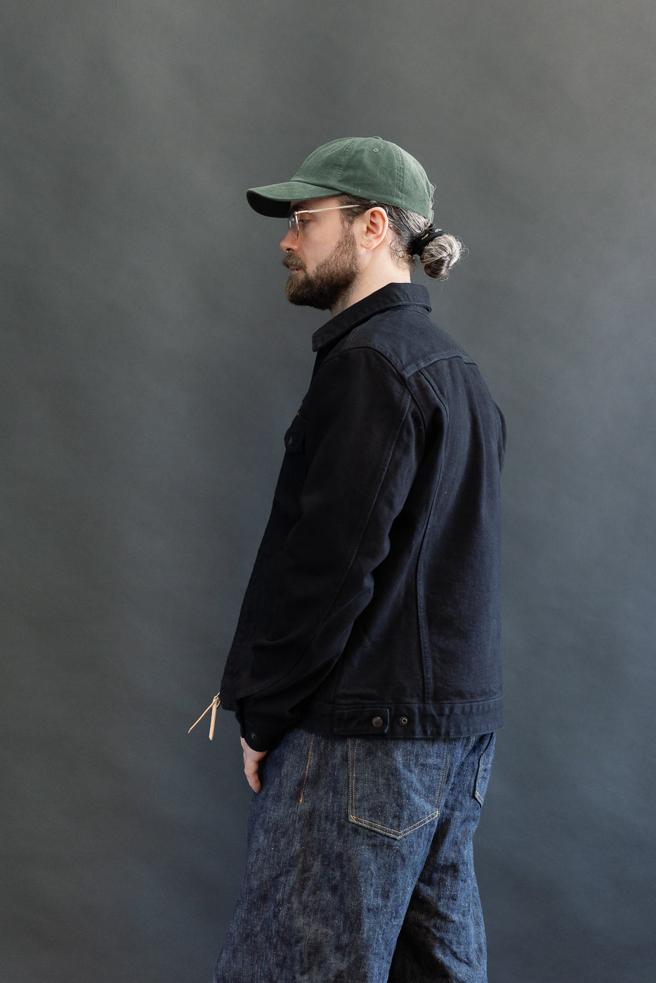 IHJ-123-OD - 14oz Broken Twill Selvedge Denim Work Jacket - Indigo Overdyed Black, worn by a bearded man in a side view. The jacket features meticulous construction with unique selvedge ID detailing.