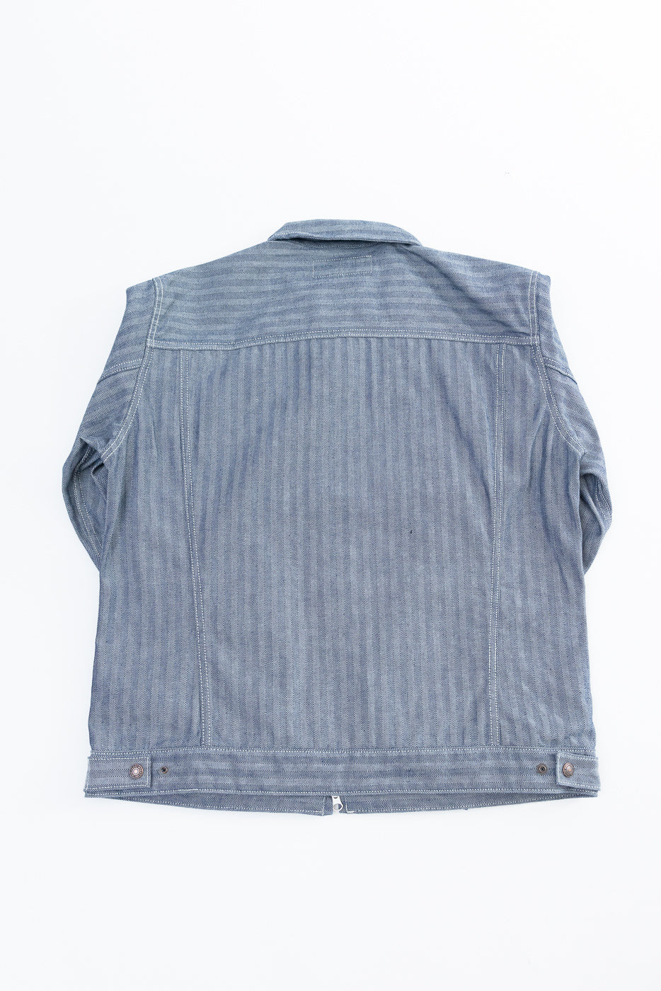 Flat lay of indigo herringbone work jacket, back side, showing collar and back hem details.