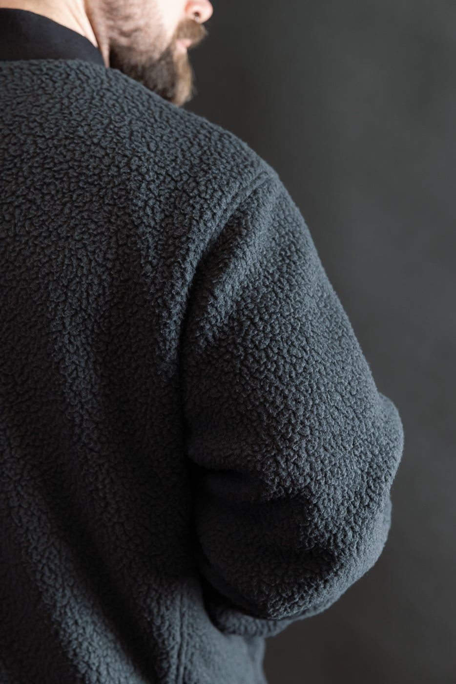 Close-up of back and sleeve texture on black reversible fleece jacket, male model, athletic build