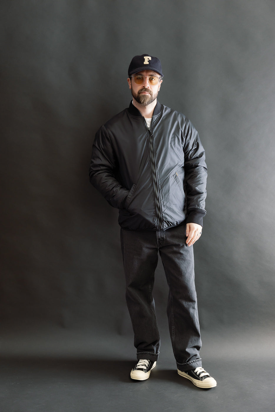 Full body front view of male model 5'9, 165lbs, athletic build wearing black reversible fleece jacket, zipped with hands in pockets.