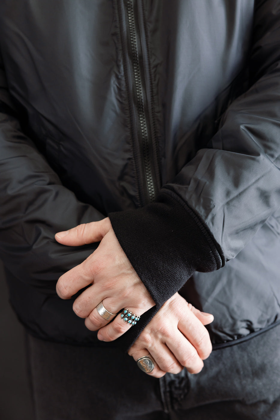 Close-up of front torso on male model wearing black reversible fleece jacket, zip and cuff details visible.