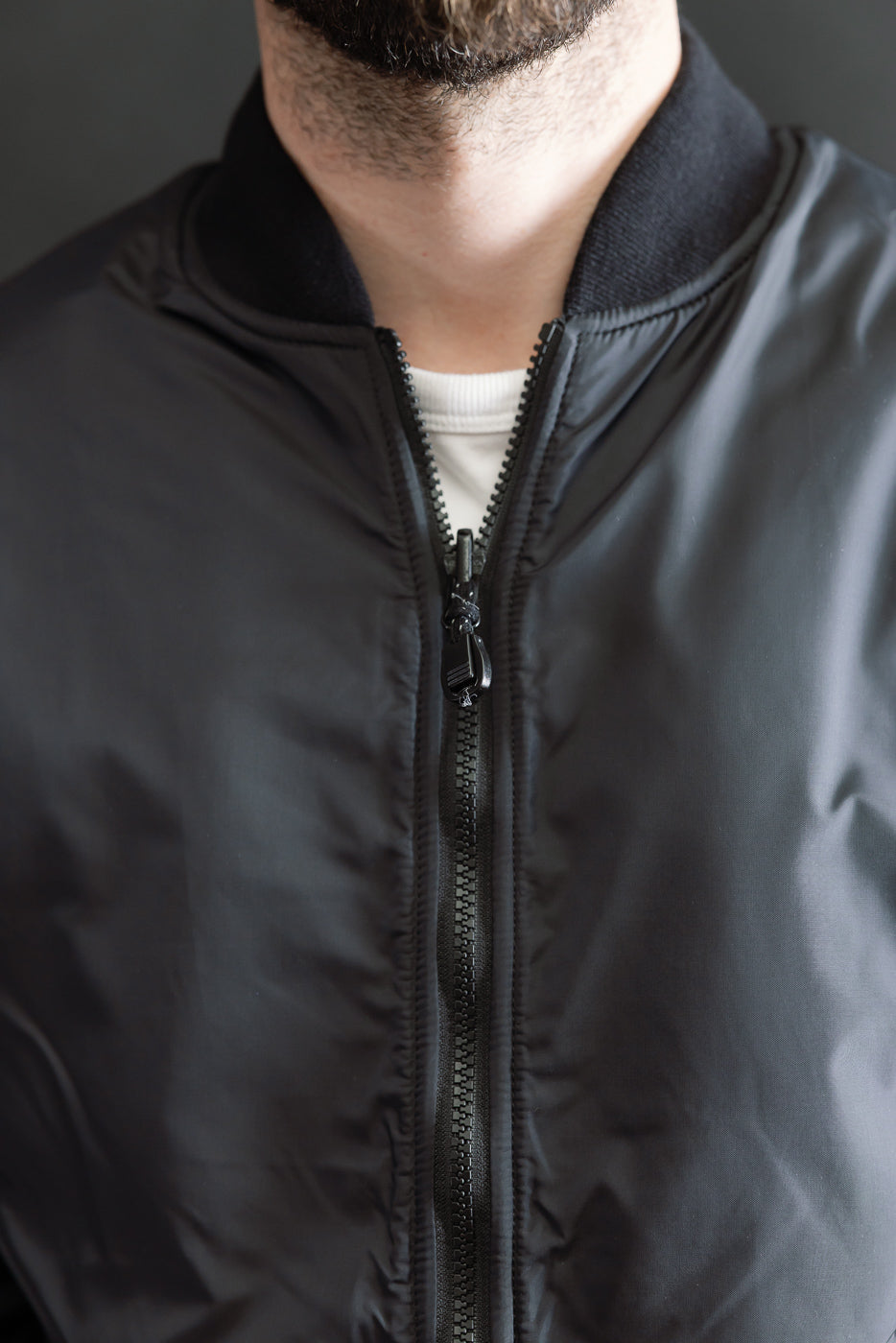 Close-up front of black reversible fleece jacket on male model, showing zipper and collar detail.
