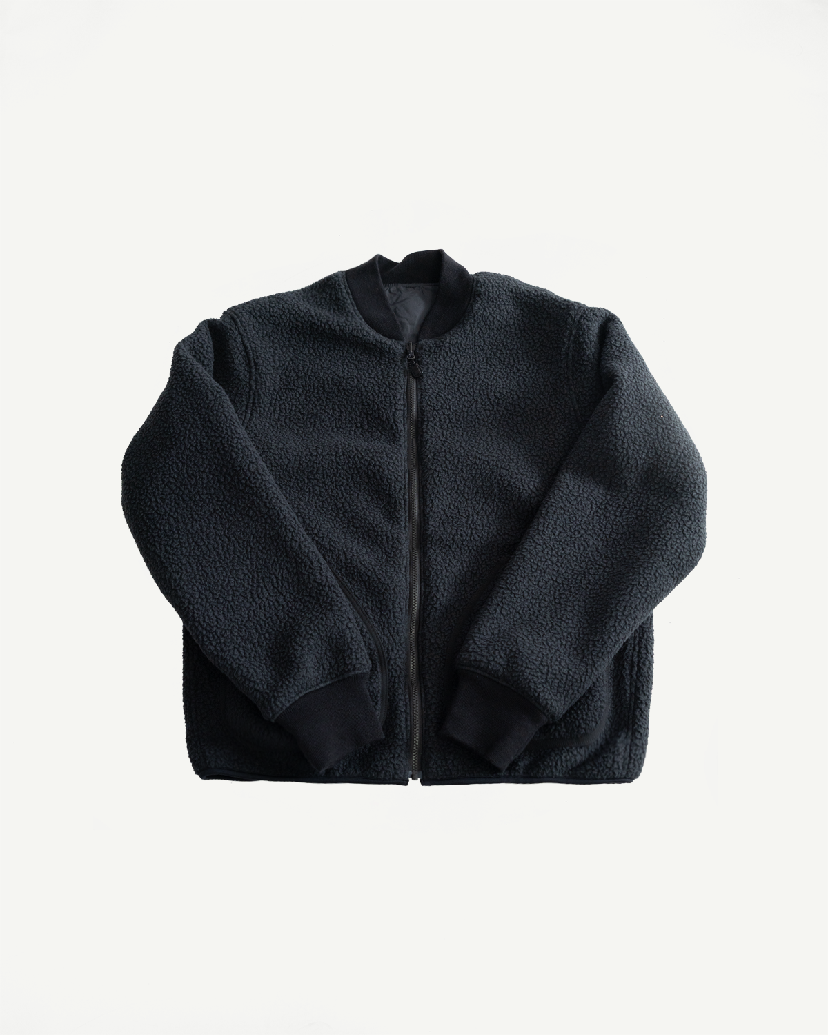 Flat lay front view of black reversible fleece jacket, full body, showing zip closure and ribbed collar.