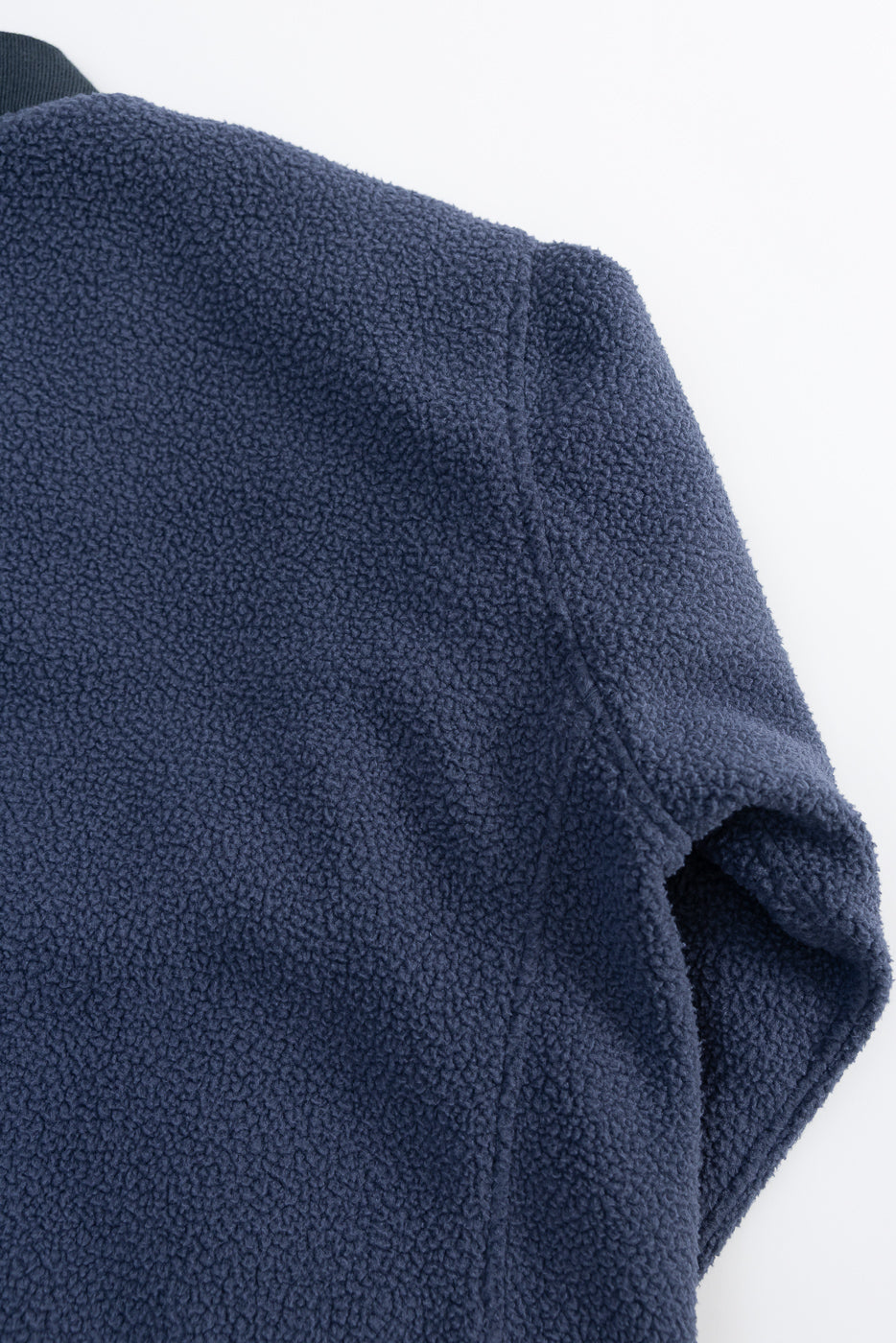 Close-up of navy reversible fleece jacket back shoulder, showing soft textured fabric