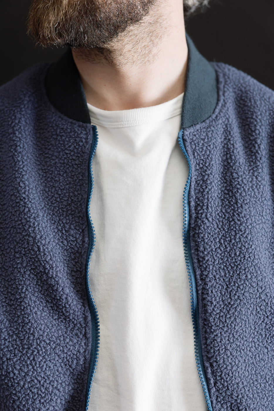 Close-up front view of navy reversible fleece jacket, visible collar, zipper, texture; male model, 5'9