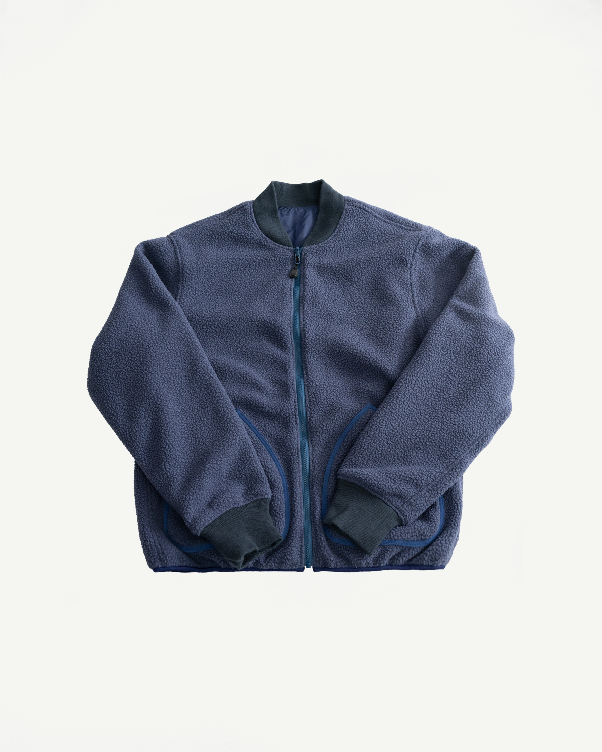 Flat lay of navy reversible fleece jacket, front side shown with full zip, ribbed collar and cuffs.