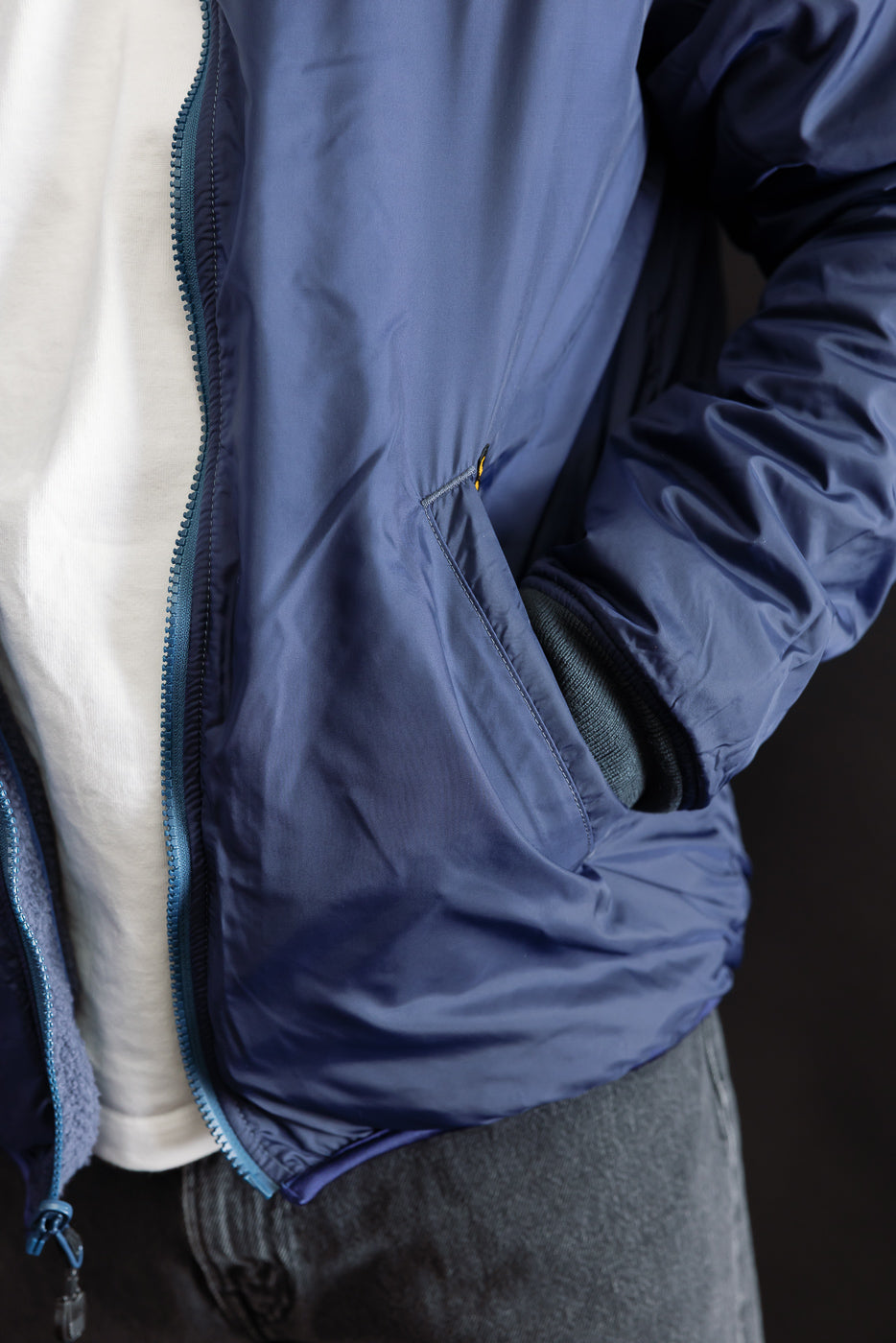 Close-up of male model wearing navy reversible fleece jacket, front side details with pocket