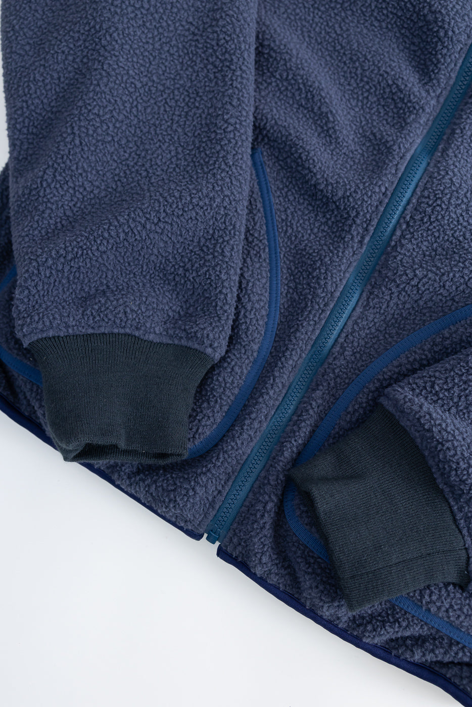 Close-up of navy reversible fleece jacket front, showing zip detail and ribbed cuffs.