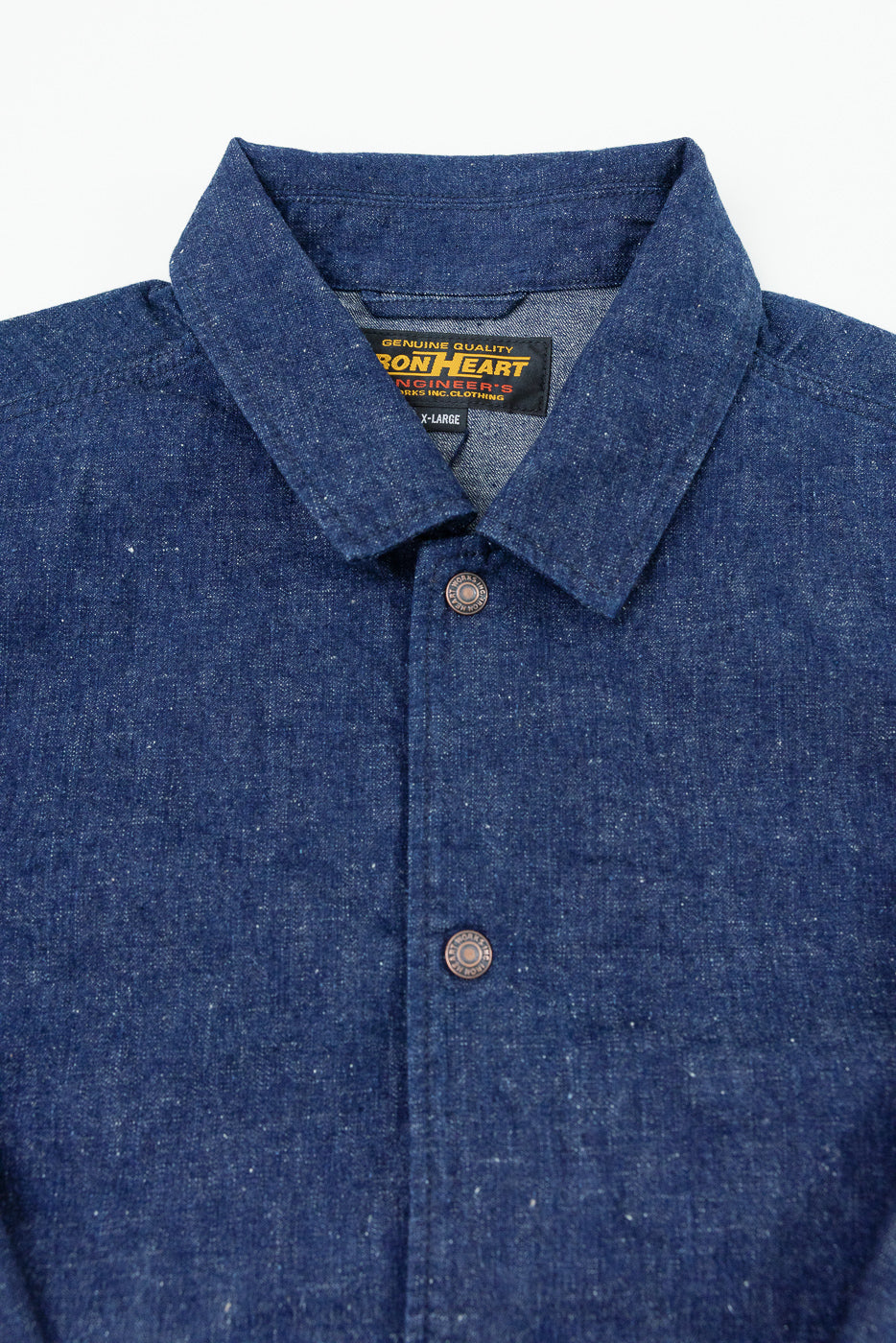 Close-up front view of blue chambray work shirt, showing collar, buttons, and Iron Heart brand tag
