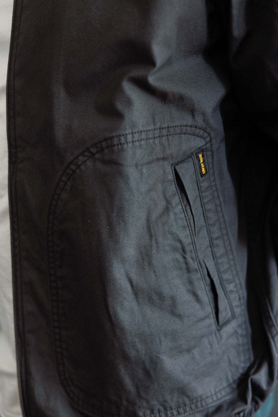 Close-up of black cargo pants side pocket, showing fabric texture and yellow tag detail