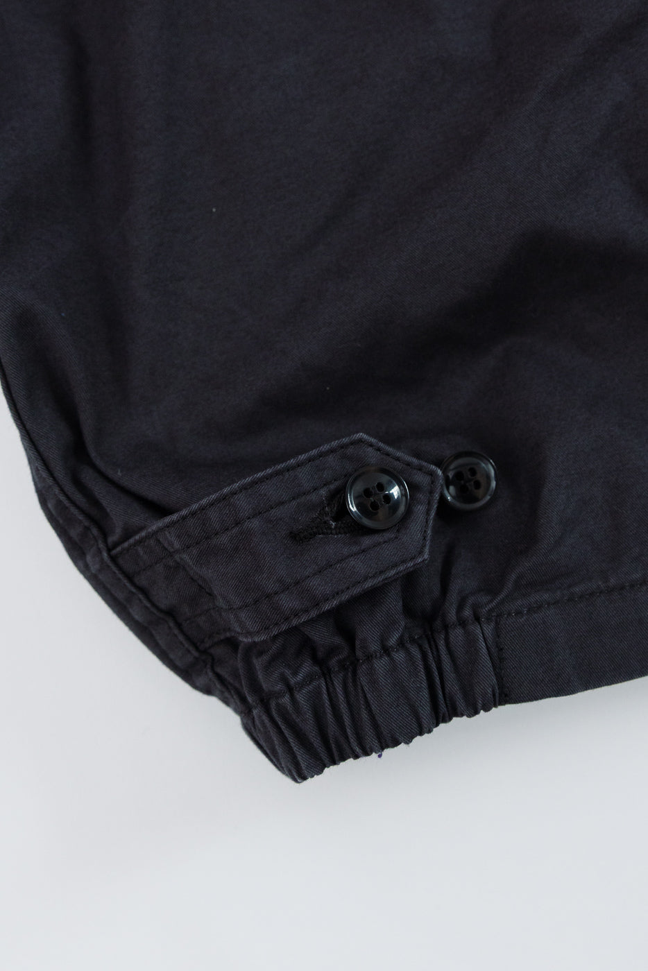 Close-up of black shirt sleeve cuff with buttons and elastic hem, front view