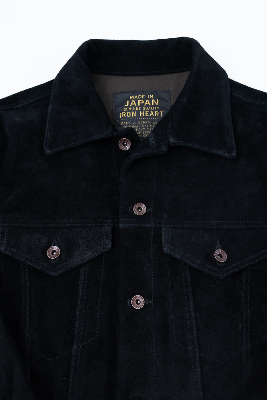 Close-up front view of black suede jacket showing collar, buttons, chest pockets, and 'Made in Japan' tag.