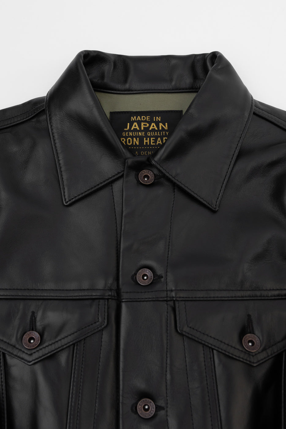 Close-up front view of black leather jacket, showcasing collar, buttons, and 'Made in Japan' tag detail.